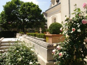 A courtyard with a stone wall, a statue, and a rose bush. - 5-star villa with a large pool, hot tub, and sauna in the Loire Valley (Montrichard Val de Cher)