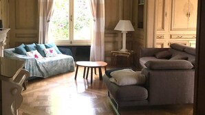 Habitació amb sofà, cadira, taula petita i làmpada.