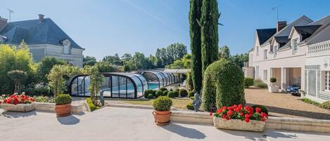 Un patio con piscina, plantas en macetas y un invernadero.