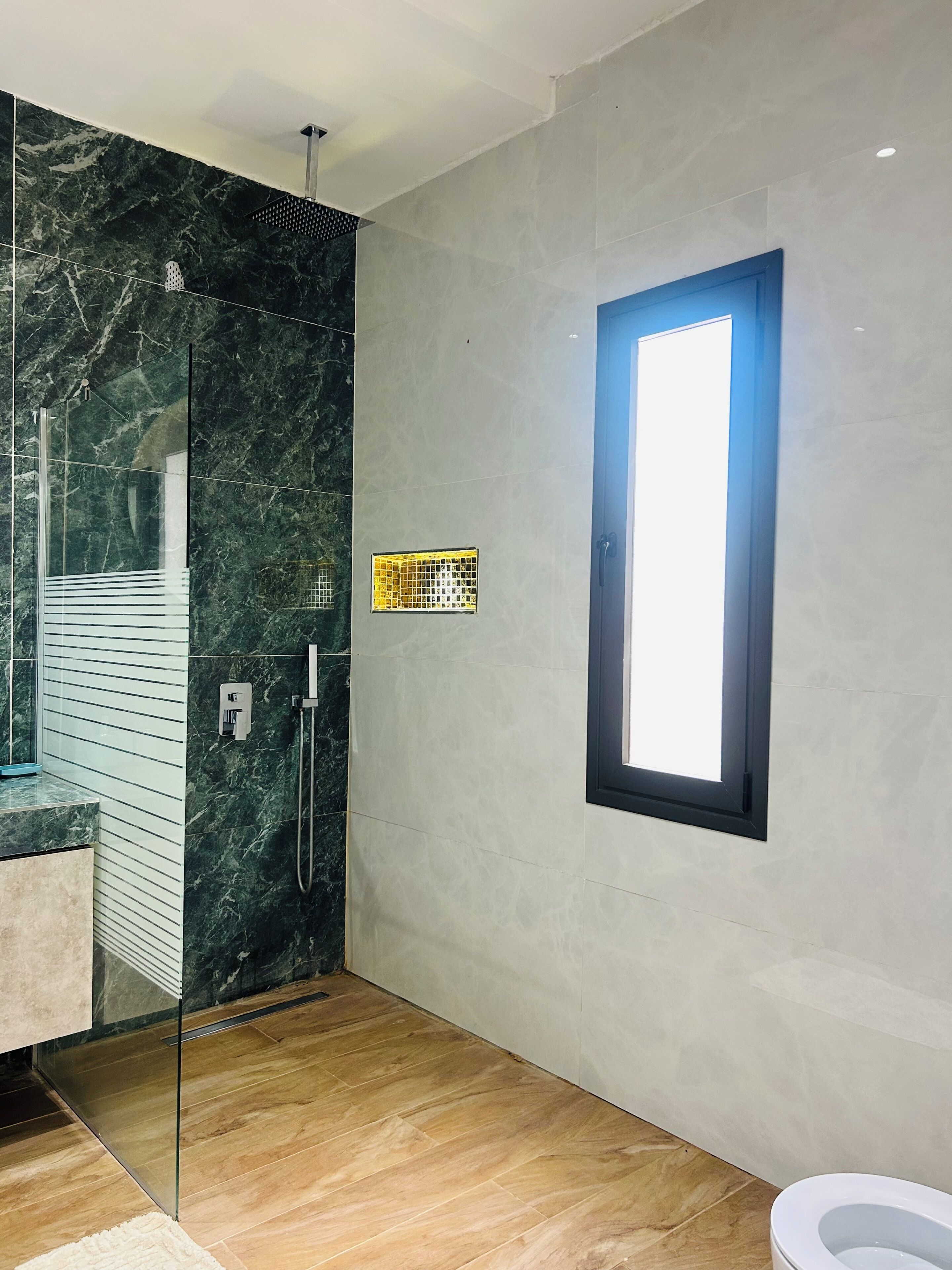 Une salle de bain moderne avec une douche à parois de verre, un lavabo intégré et des toilettes.