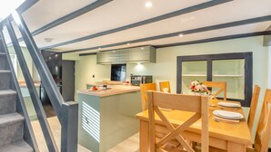 Cozinha moderna com ilha central, mesa de jantar de madeira e cadeiras.