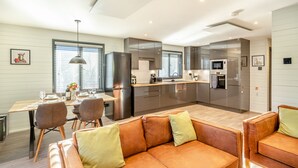 Une cuisine moderne équipée d’appareils électroménagers en acier inoxydable, un coin repas avec une table et des chaises, et un espace détente avec un canapé.