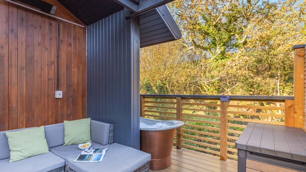 Une terrasse en bois avec un espace salon, un jacuzzi et une table.