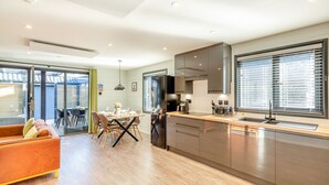 Une cuisine moderne avec un coin repas, de grandes fenêtres et une porte-fenêtre coulissante donnant sur un espace extérieur.