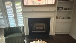 A living room with a fireplace, a television, a sofa, and a coffee table with books and a remote control. - Beautiful designer home located near SouthEnd, LoSo, Rail and Uptown (Charlotte)