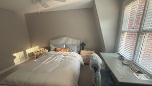 A bedroom with a bed, a desk, a chair, a ceiling fan, and a window with blinds. - Beautiful designer home located near SouthEnd, LoSo, Rail and Uptown (Charlotte)