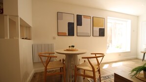 Un coin repas comprenant une table ronde, quatre chaises et des œuvres d’art abstraites accrochées au mur.