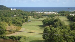 A coastal landscape with a golf course, lush greenery, and a distant view of the ocean. - Spacious 2BR Apartment in Cap Estate, Saint Lucia - Walk to Beaches (Gros Islet)