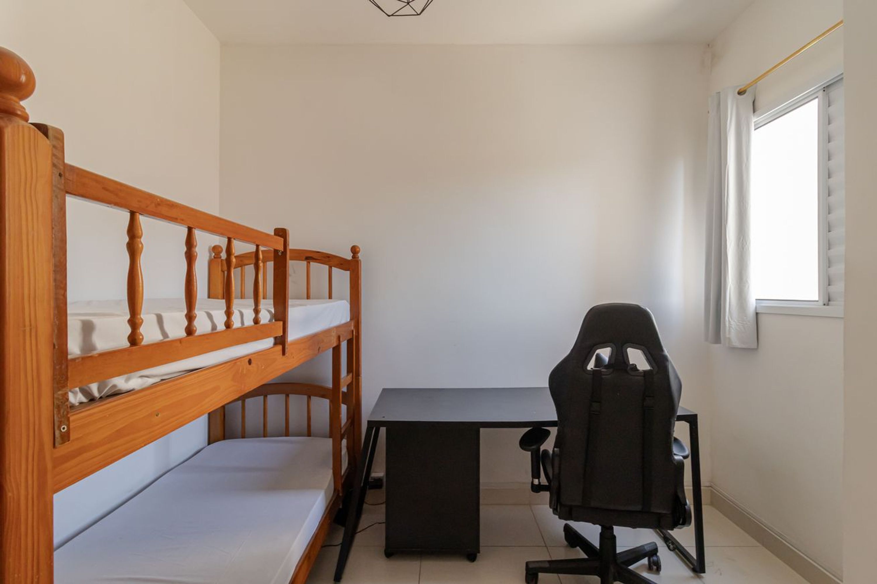A room with a bunk bed, a desk, and a gaming chair.