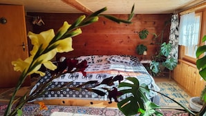 Dormitorio de cabaña de madera con una cama, una ventana y varias plantas.