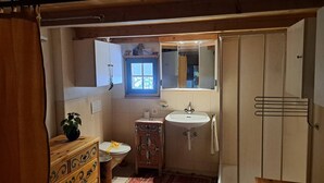 Un baño pequeño con un mueble de madera, un lavamanos y un inodoro.