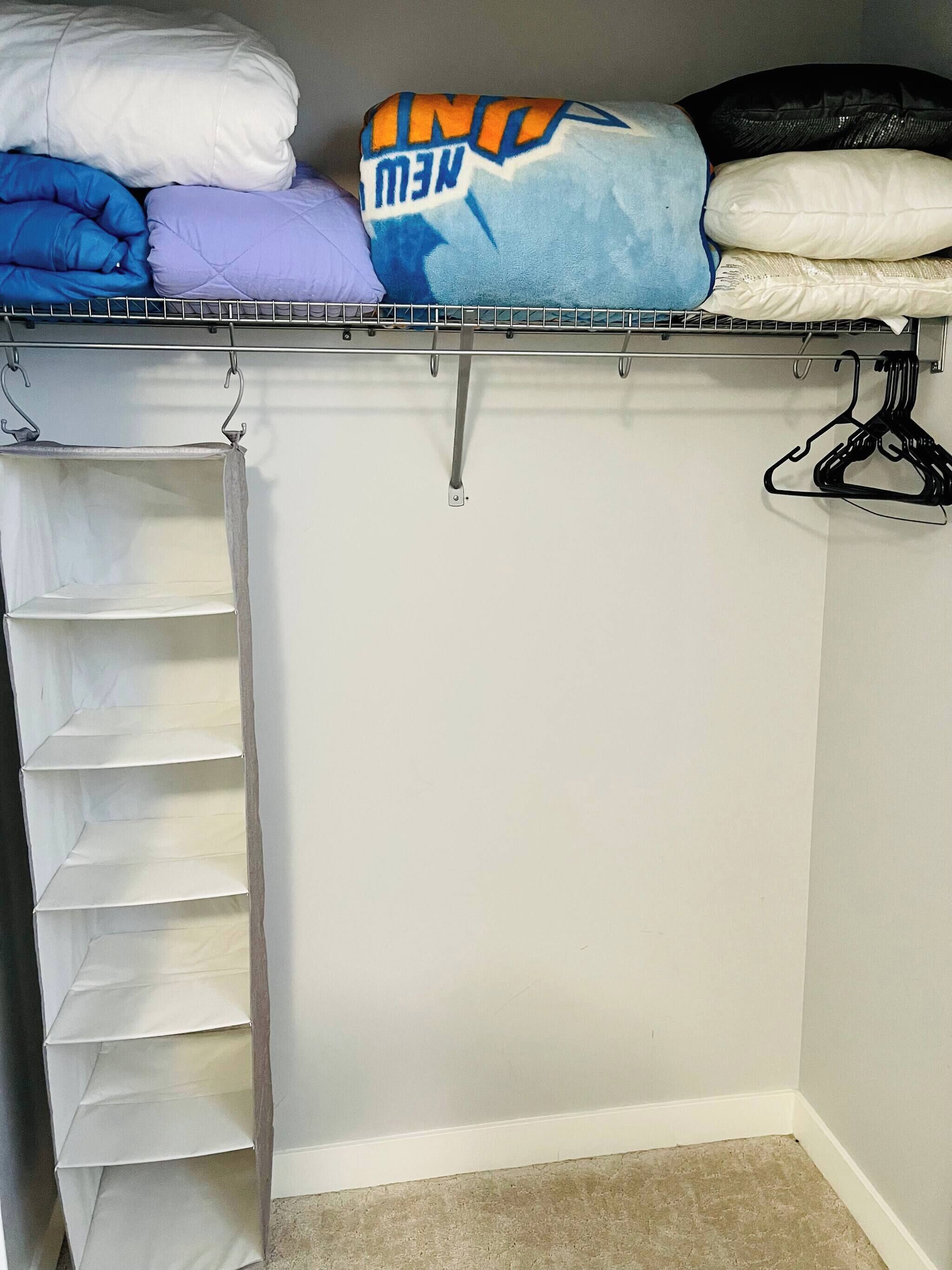 A closet with shelves, hanging space, and a storage unit.