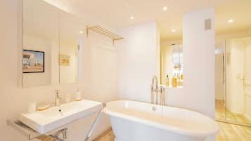 Un baño moderno con una bañera independiente, un espejo grande y un mueble de tocador con lavabo.