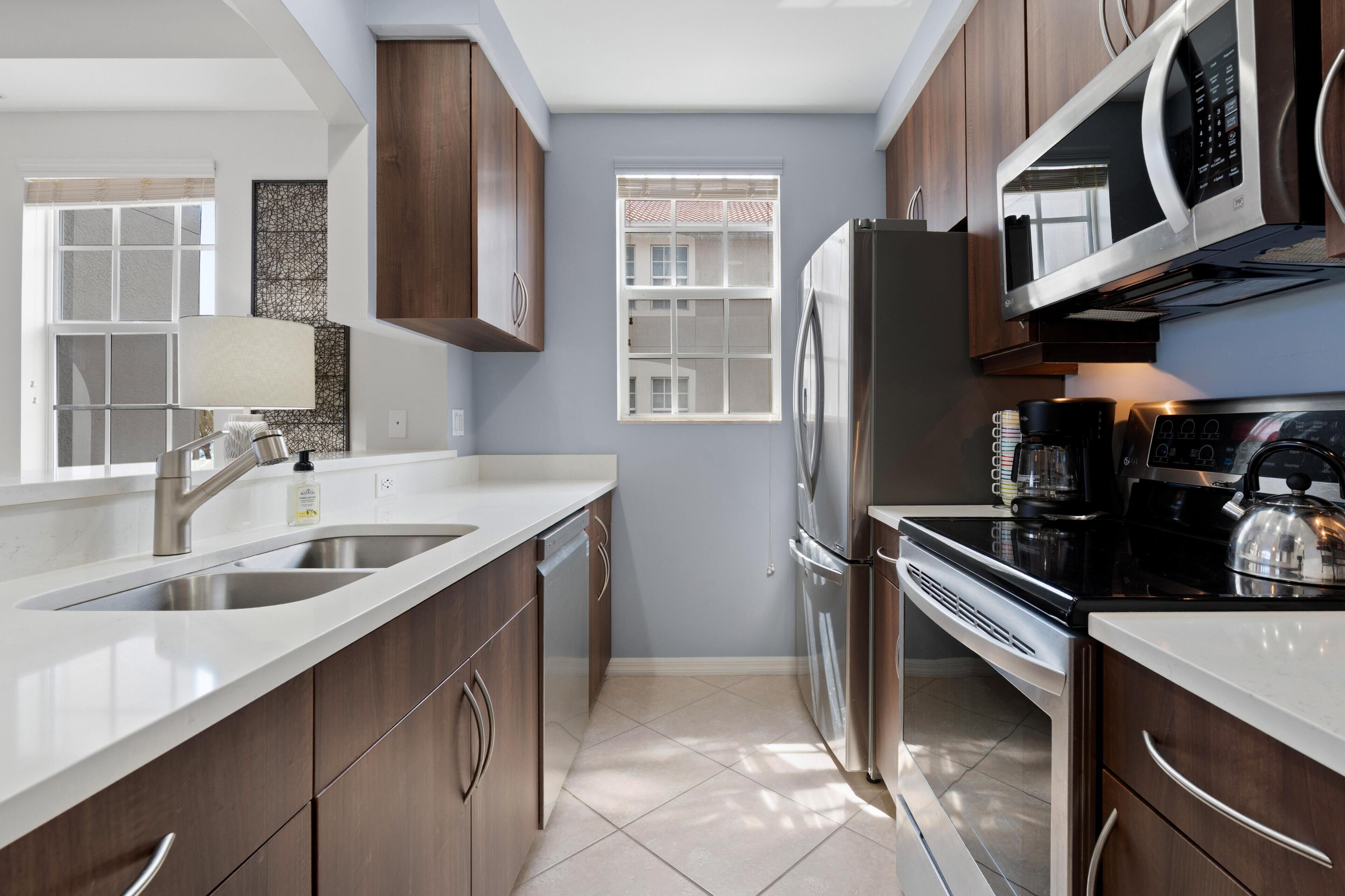 A modern kitchen with stainless steel appliances, a double sink, and wooden cabinets.