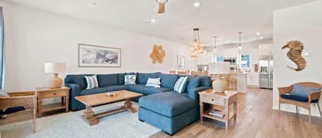A spacious living room with a sectional sofa, wooden coffee table, and a ceiling fan.
