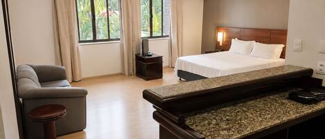 A hotel room with a bed, a desk, a chair, and a TV.