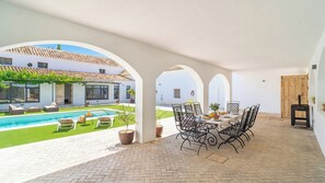 A covered outdoor area with a pool, lounge chairs, and a dining table with chairs. - Peña de los Enamorados Antequera by Ruralidays (Málaga)