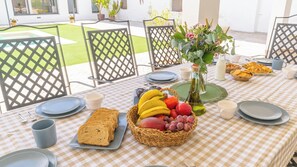 Ein karierter Tisch mit Tellern, Schüsseln und einer Obst- und Brotkörbchen.