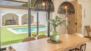 A dining area with a view of a swimming pool, a wooden table, chairs, and a green vase with flowers. - Peña de los Enamorados Antequera by Ruralidays (Málaga)