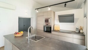 Eine moderne Küche mit Spülbecken aus Edelstahl, einer Mikrowelle und einem eingebauten Backofen.