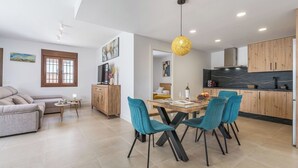 A modern living space with a dining area, kitchen, and seating area. - Oasis de Cáñar by Ruralidays (Granada)