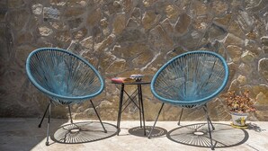 Two blue wire mesh chairs, a small round table, and a potted plant against a stone wall. - Oasis de Cáñar by Ruralidays (Granada)