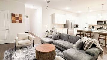 A modern living room with a sectional sofa, a round coffee table, and a ceiling fan.