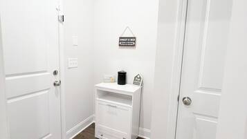 A hallway with white doors, a white cabinet, and a welcome mat.