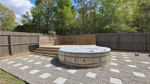 Un bain à remous entouré d’une terrasse en bois et d’un espace recouvert de gravier.