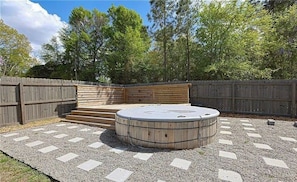 A hot tub surrounded by a wooden deck and a gravel area. - The Morgan House | Pool · Deck · Walk to the Taps (Fayetteville)