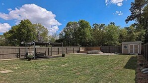 Un jardin avec une clôture en bois, un petit abri de jardin et un espace patio.
