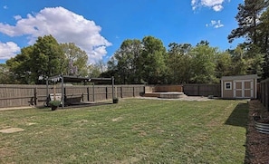 A backyard with a wooden fence, a small shed, and a patio area. - The Morgan House | Pool · Deck · Walk to the Taps (Fayetteville)