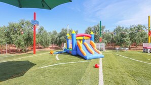 Un parque infantil con tobogán y juegos hinchables sobre césped artificial.