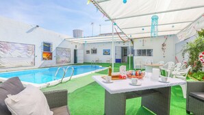 Un área de piscina con una mesa lista para el desayuno, asientos exteriores y un patio cubierto.