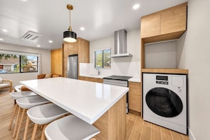 A modern kitchen with a central island, built-in appliances, and a large window. - The Madison | Walk to Adams Ave & Cafés (San Diego)