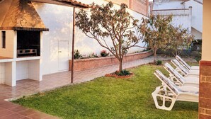 An outdoor patio with a grill, a small tree, and a row of white lounge chairs. - Brisa del Mar Vélez-Málaga by Ruralidays (Málaga)