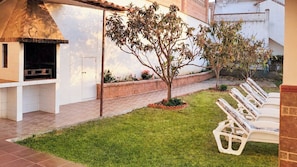 An outdoor patio with a grill, a small tree, and a row of white lounge chairs. - Brisa del Mar Vélez-Málaga by Ruralidays (Málaga)
