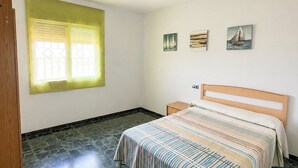 A bedroom with a bed, a window with blinds, a nightstand, and three wall-mounted paintings. - Brisa del Mar Vélez-Málaga by Ruralidays (Málaga)