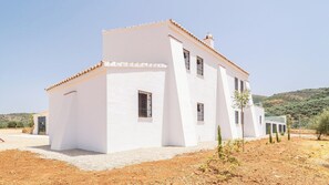 A white building with a flat roof and multiple windows, surrounded by a dry, hilly landscape. - Cortijo La Alcaidía Archidona by Ruralidays (Málaga)