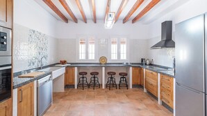 Una cocina moderna con vigas de madera, un refrigerador de acero inoxidable y una isla central con taburetes.