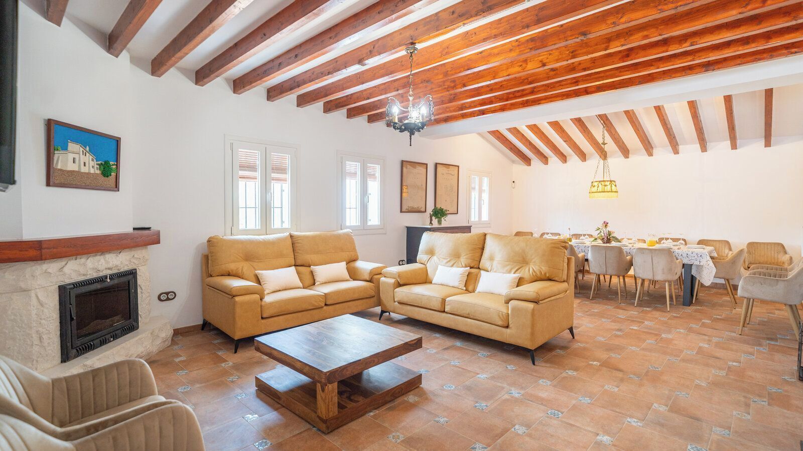 A living room with a fireplace, two sofas, a coffee table, and a dining area with chairs and a table.