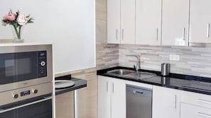 A modern kitchen with stainless steel appliances, a black countertop, and a tiled backsplash. - Casa del Tío Paco Montecorto by Ruralidays (Málaga)