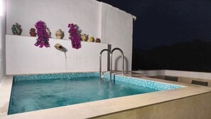 A swimming pool with a tiled edge, a metal ladder, and decorative items on a white wall. - Casa del Tío Paco Montecorto by Ruralidays (Málaga)