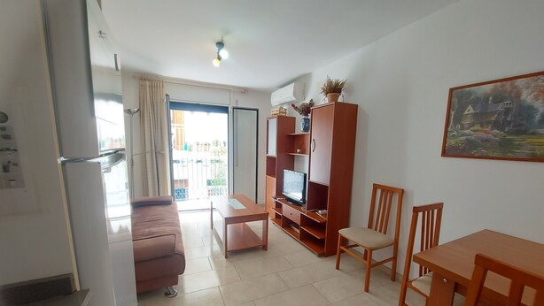A living room with a sofa, TV stand, and dining table. - Apartment 'Nou 8' with Balcony, Wi-Fi and Air Conditioning (Sitges)