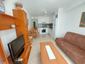 A living room with a TV, sofa, and a dining area with chairs. - Apartment 'Nou 8' with Balcony, Wi-Fi and Air Conditioning (Sitges)