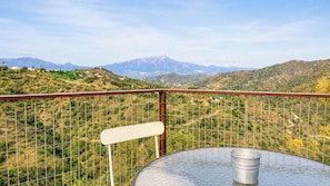 A balcony with a metal railing, a metal bucket, and a table. - Casa Viladán Colmenar by Ruralidays (Málaga)