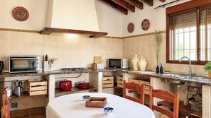 A compact kitchen with a microwave, stove, and wooden cabinets. - Casa Viladán Colmenar by Ruralidays (Málaga)