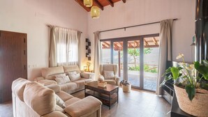 A spacious living room with a sofa set, a coffee table, and a large sliding glass door leading to an outdoor area. - La Casilla del Mirador del Torcal Villanueva de la Concepción by Ruralidays (Province of Málaga)