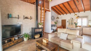A living room with a TV, sofa, wooden coffee table, and a fireplace. - La Casilla del Mirador del Torcal Villanueva de la Concepción by Ruralidays (Province of Málaga)
