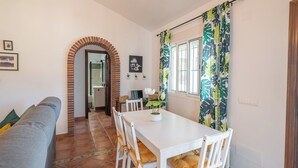 A dining area with a white table, chairs, and a brick archway leading to a bathroom. - El Rincón de Esther Cómpeta by Ruralidays (Málaga)